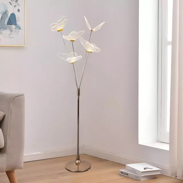 Lámpara de piso con mariposas LED junto a sofá para living luminoso