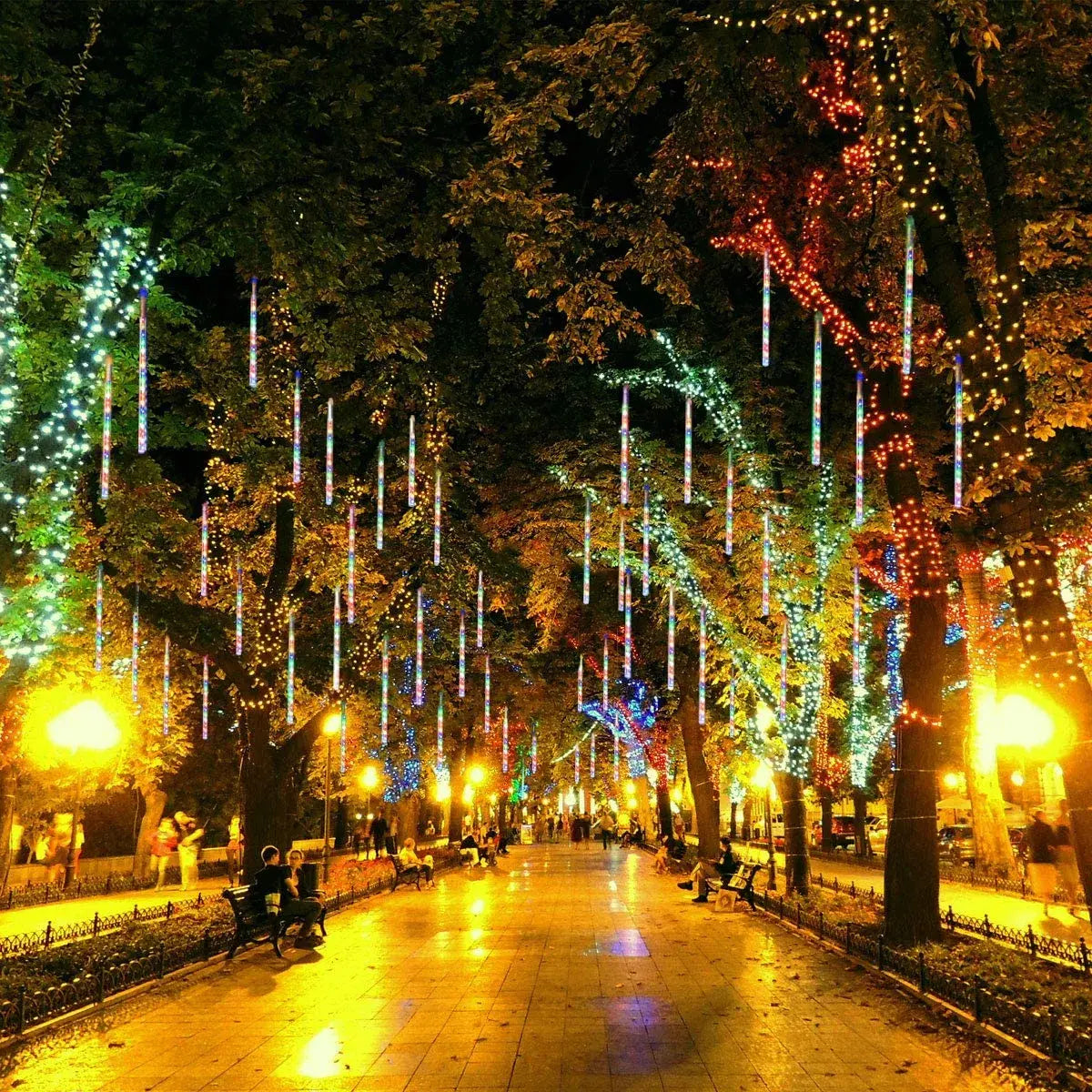 Tubos LED efecto meteorito decorando árboles en celebración nocturna